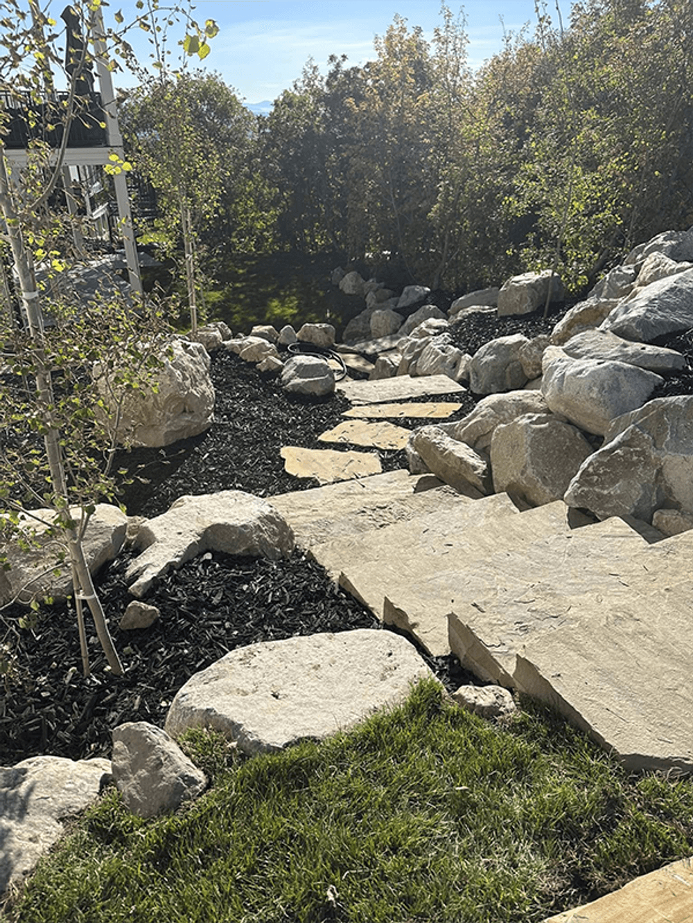 Stone pathway with landscaped rocks and greenery in a serene outdoor setting.
