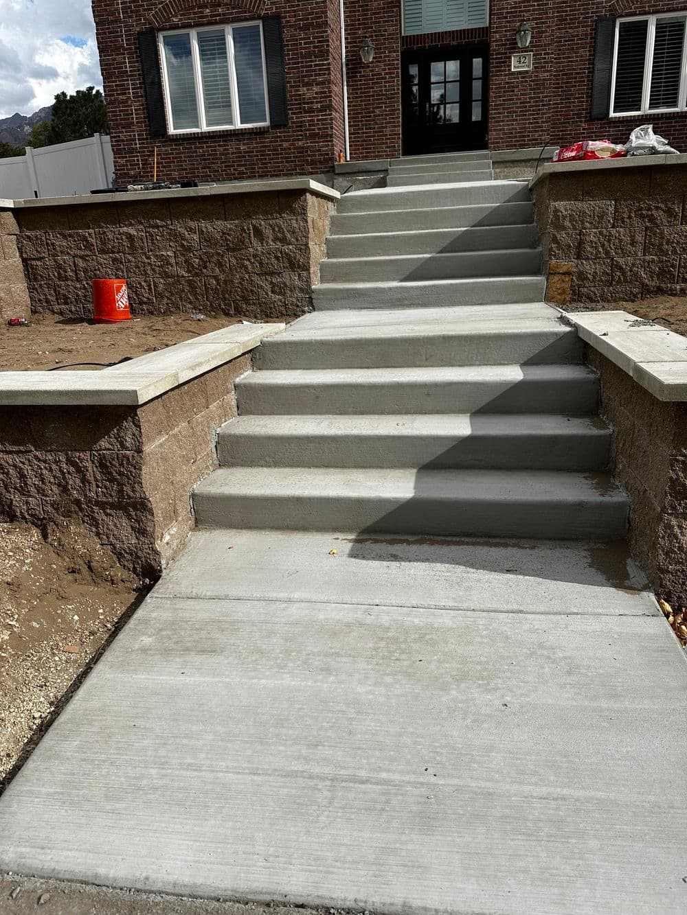 Newly finished concrete steps leading to a brick building entrance with clean lines and bright sunlight.