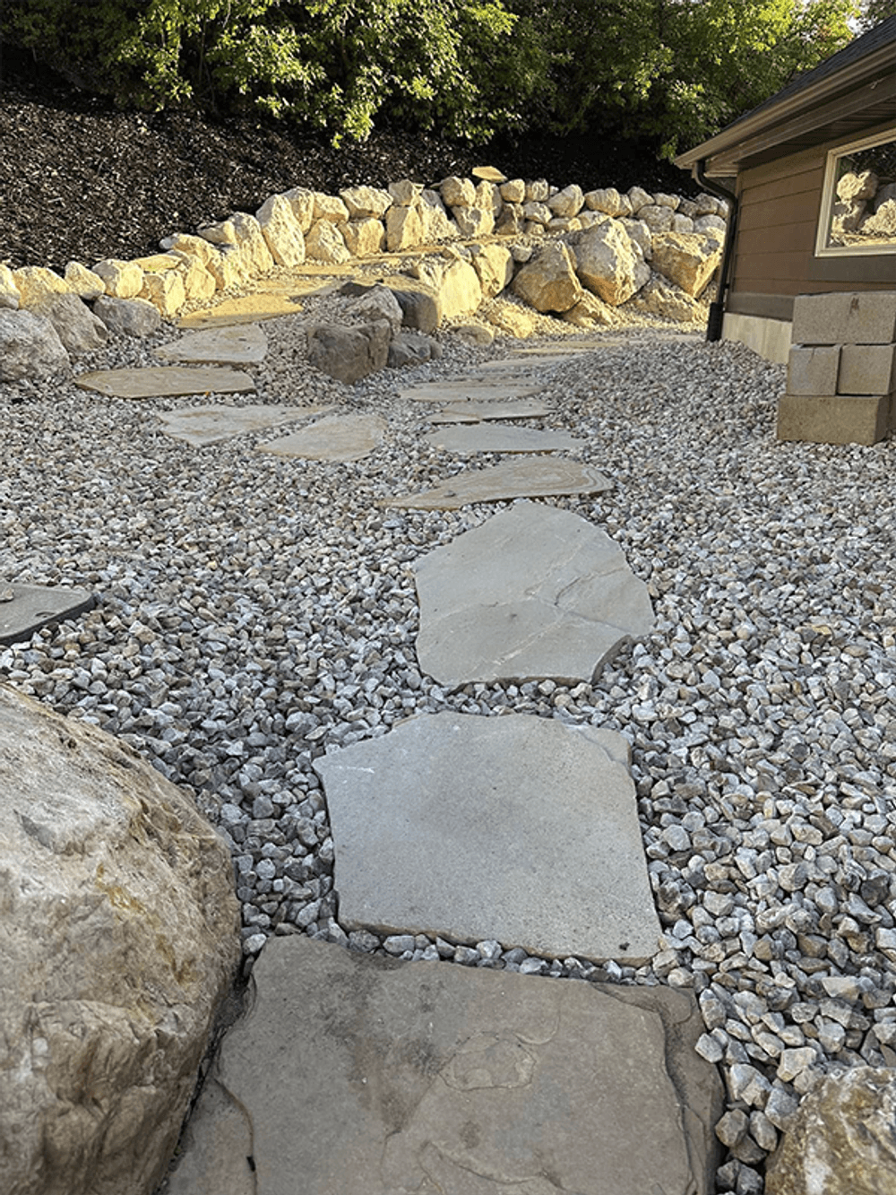Stone pathway surrounded by gravel and landscaping rocks leading to a building.