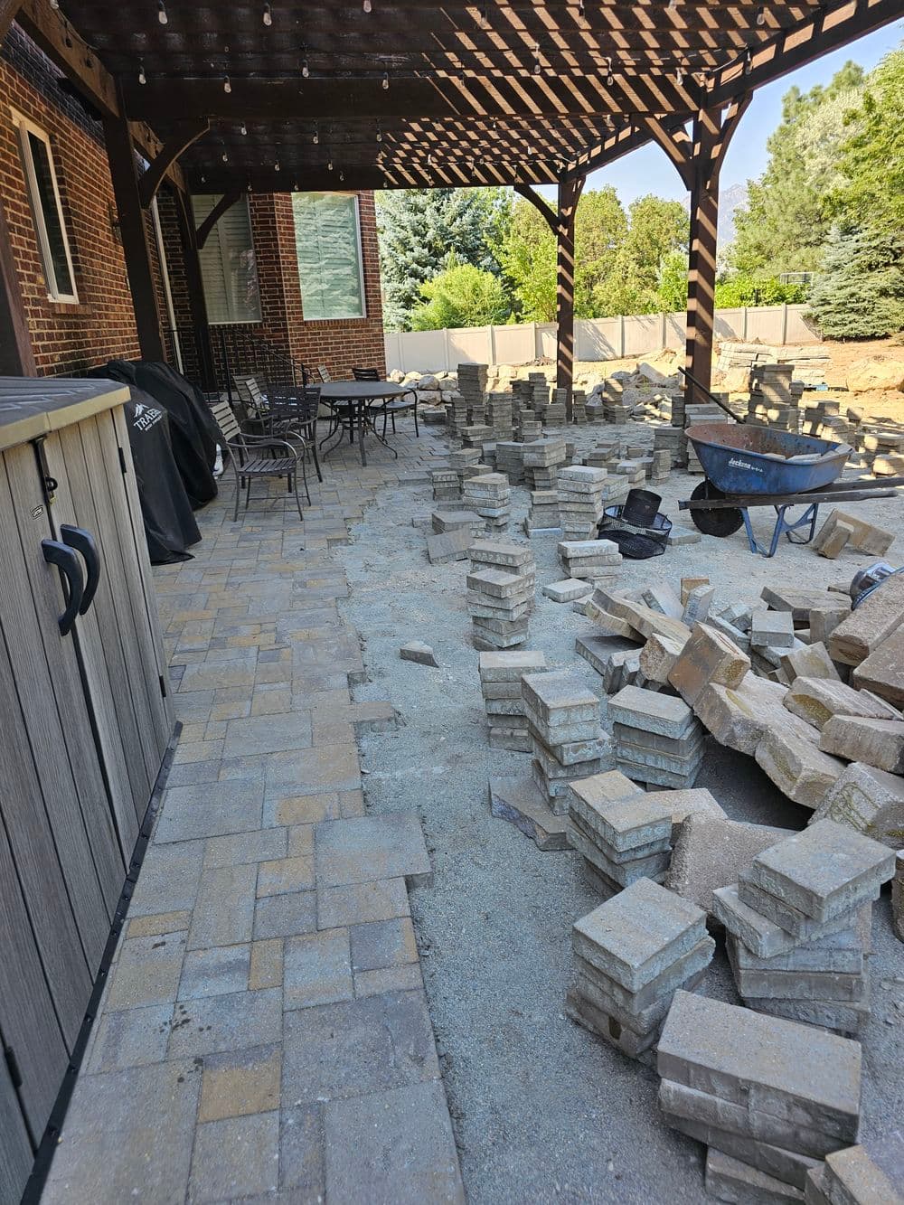 Renovated patio area with stacked stone pavers and outdoor furniture under a wooden pergola.
